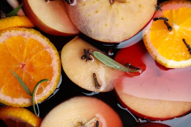 Tasty mulled wine with spices as background, closeup