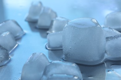 Many crystal clear ice cubes on light surface, selective focus. Space for text