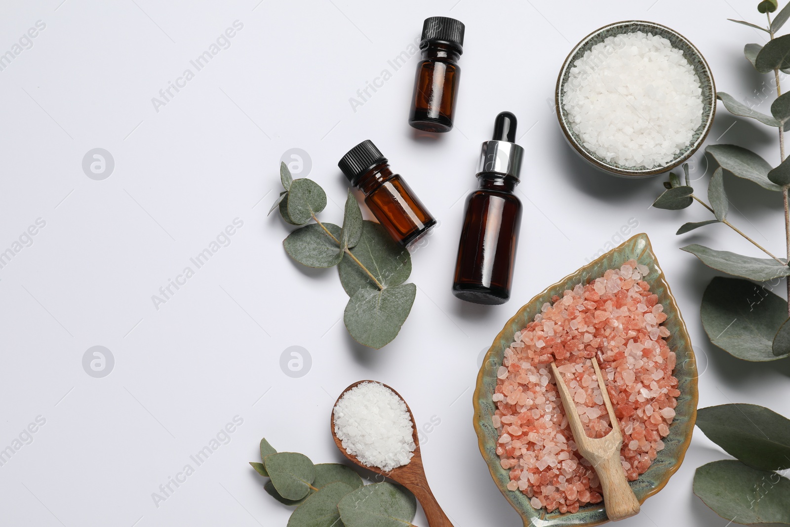 Photo of Aromatherapy products. Bottles of essential oil, sea salt and eucalyptus leaves on white background, flat lay. Space for text