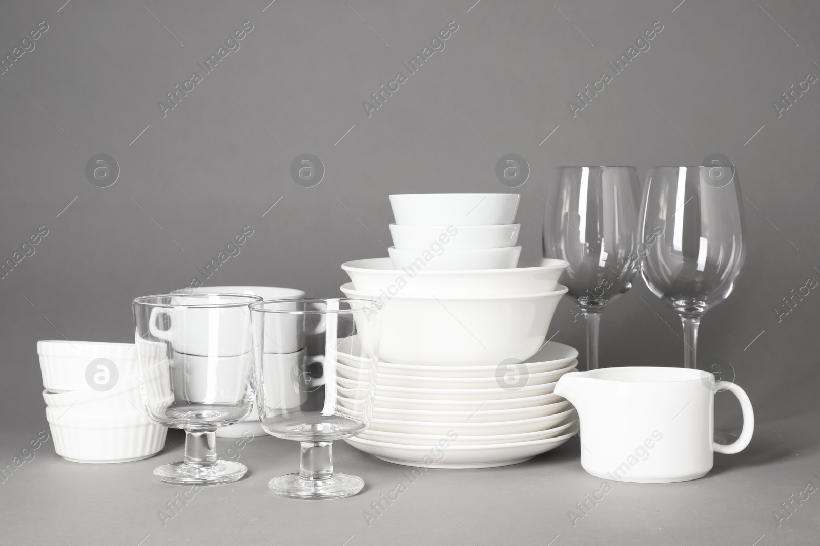 Photo of Set of clean tableware on grey background. Washing dishes