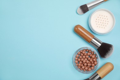 Photo of Different face powders and brushes on light blue background, flat lay. Space for text