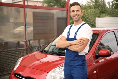 Male worker standing near clean vehicle at car wash