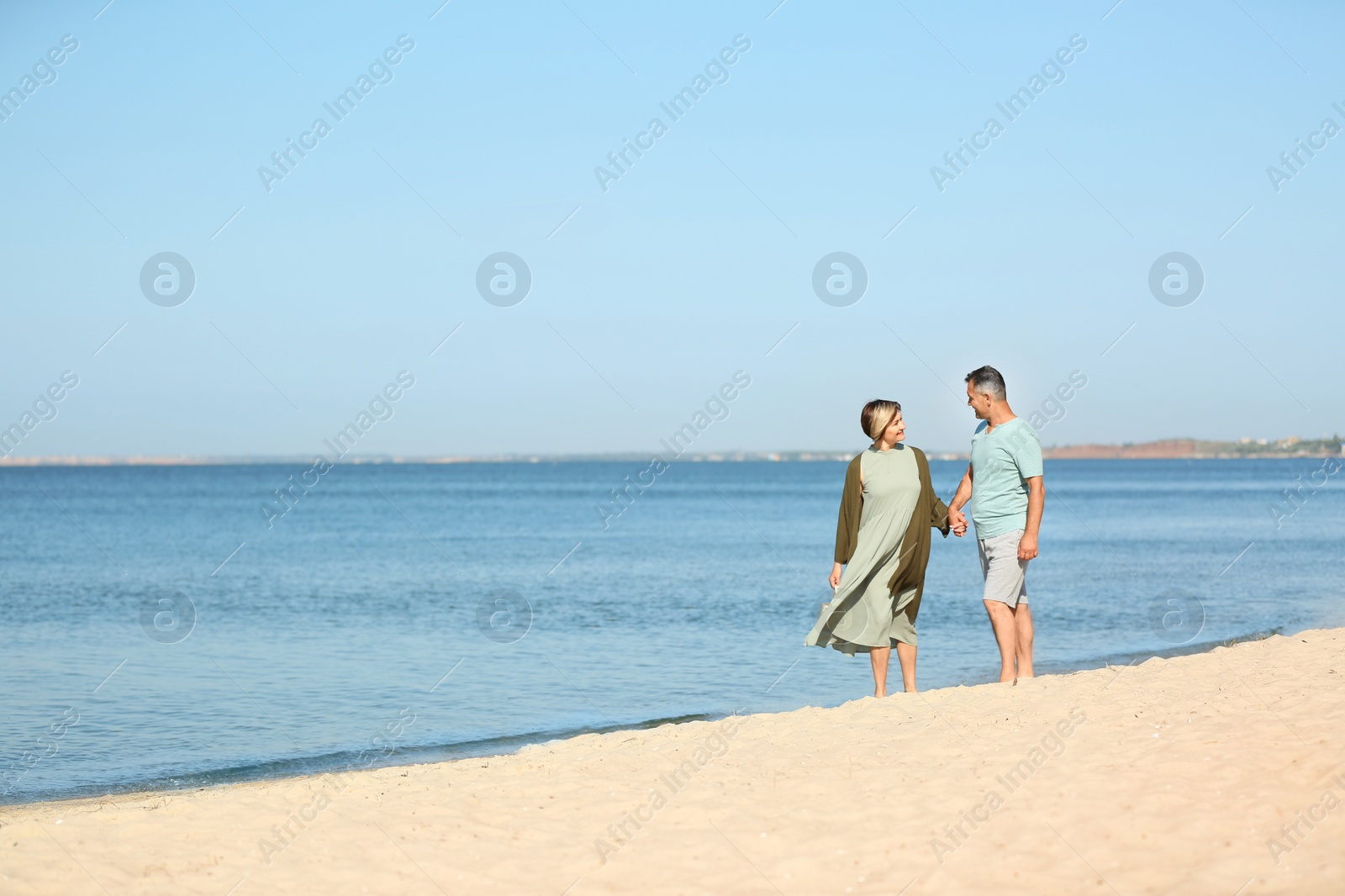 Photo of Happy mature couple walking at beach on sunny day