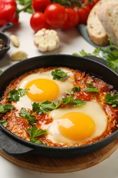 Delicious shakshuka in frying pan on white table, closeup