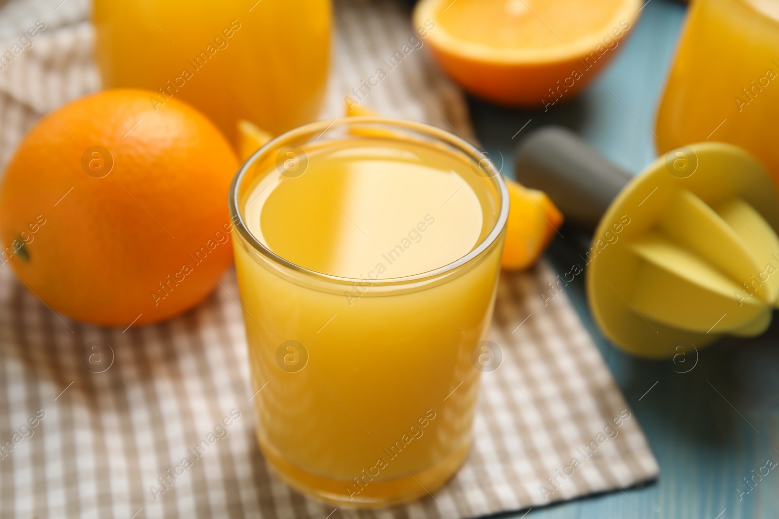 Photo of Freshly made juice, oranges and reamer on blue wooden table, closeup