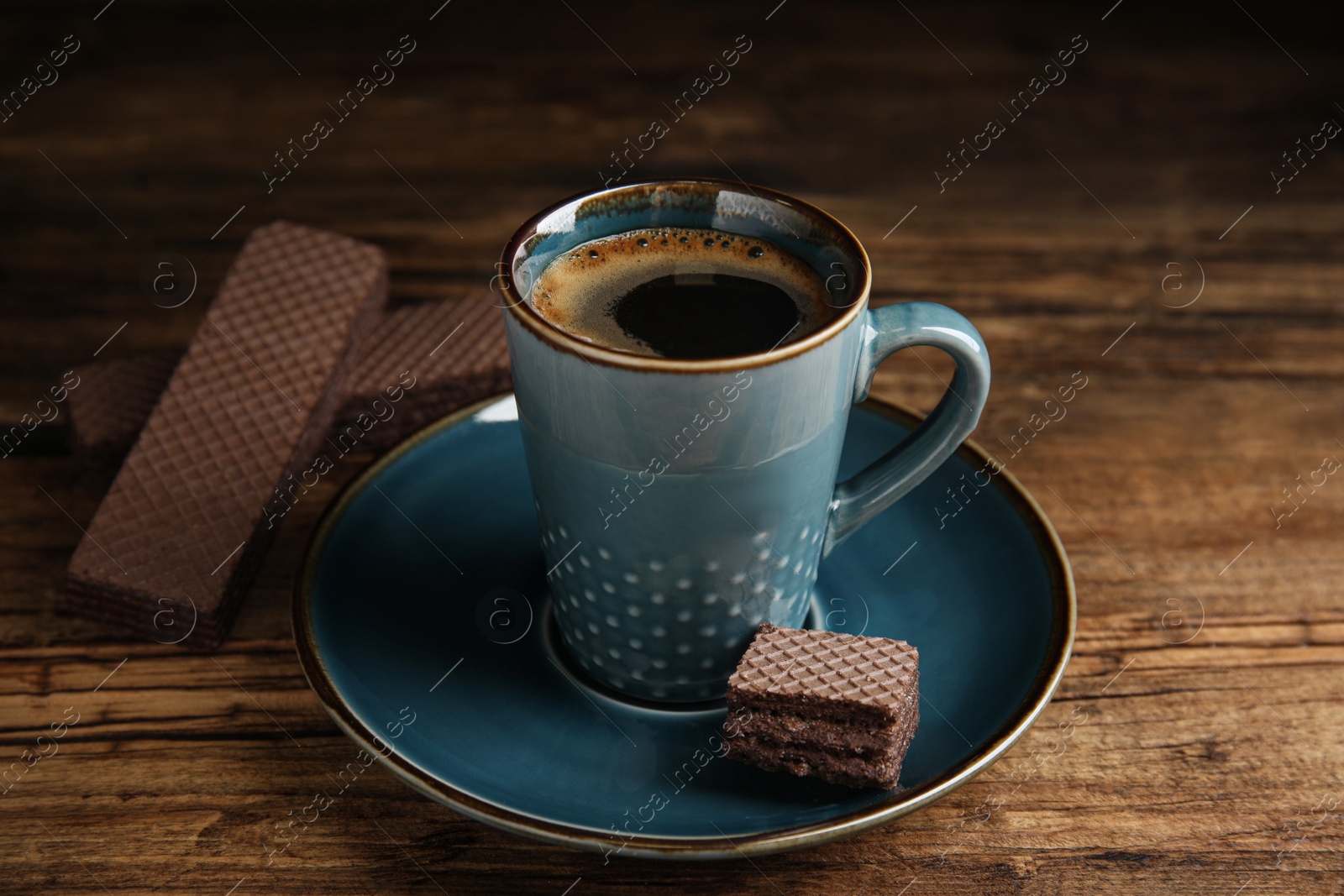 Photo of Delicious wafer and coffee on wooden table