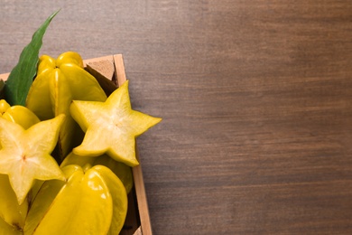 Delicious carambola fruits on wooden table, top view. Space for text