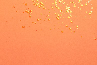 Photo of Shiny bright glitter on coral background, flat lay. Space for text