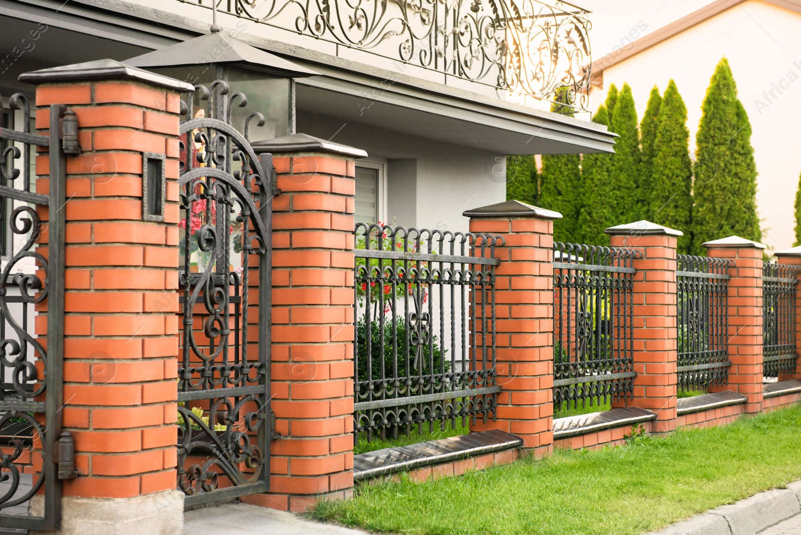 Photo of Beautiful brick fence with iron railing outdoors