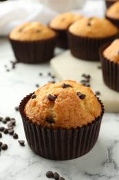 Delicious sweet muffin with chocolate chips on white marble table, closeup