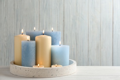 Photo of Burning candles in tray on table. Space for text