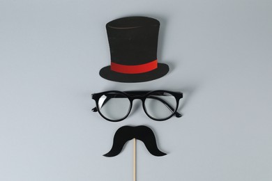 Photo of Fake mustache with party prop, paper hat and glasses on grey background, top view