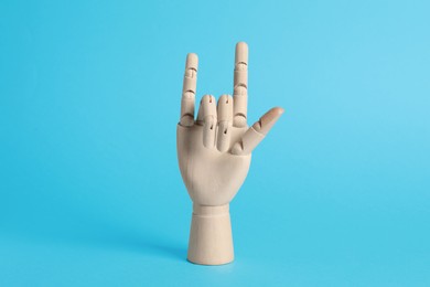 Photo of Wooden hand model on light blue background. Mannequin part