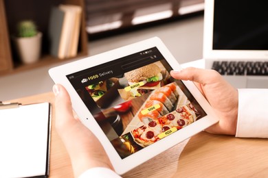 Photo of Man using tablet for ordering food online at work, closeup. Concept of delivery service