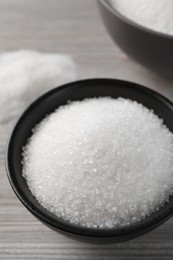 Photo of Granulated sugar on light wooden table, closeup