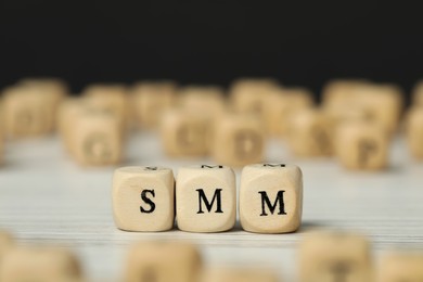 Small cubes with letters SMM on white wooden table