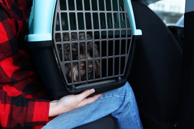 Woman with pet carrier travelling with her dog by car, closeup. Safe transportation