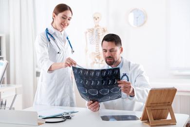 Orthopedists examining X-ray picture at desk in clinic