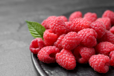 Photo of Delicious fresh ripe raspberries on black table, closeup