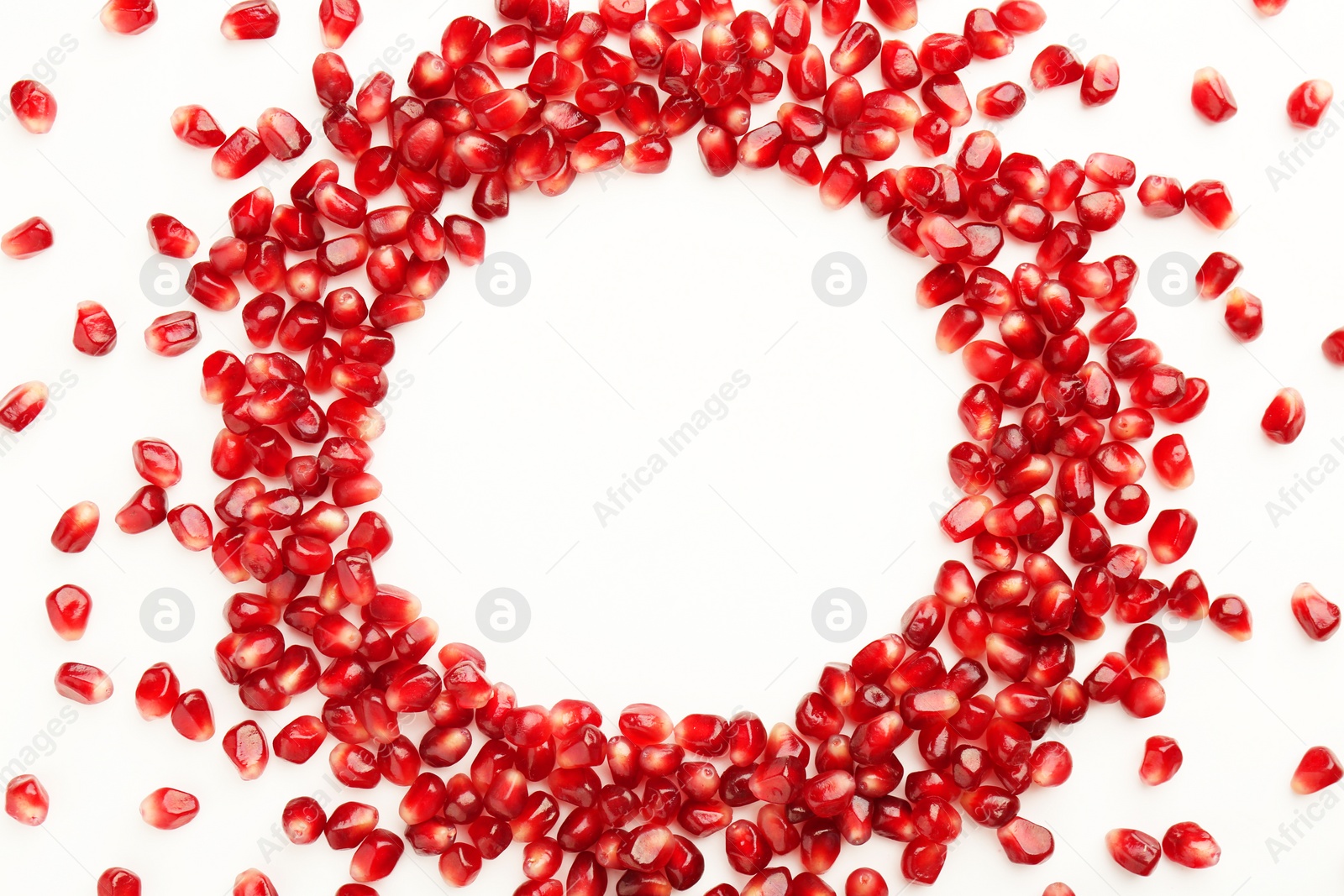 Photo of Frame made of ripe juicy pomegranate grains on white background, top view. Space for text