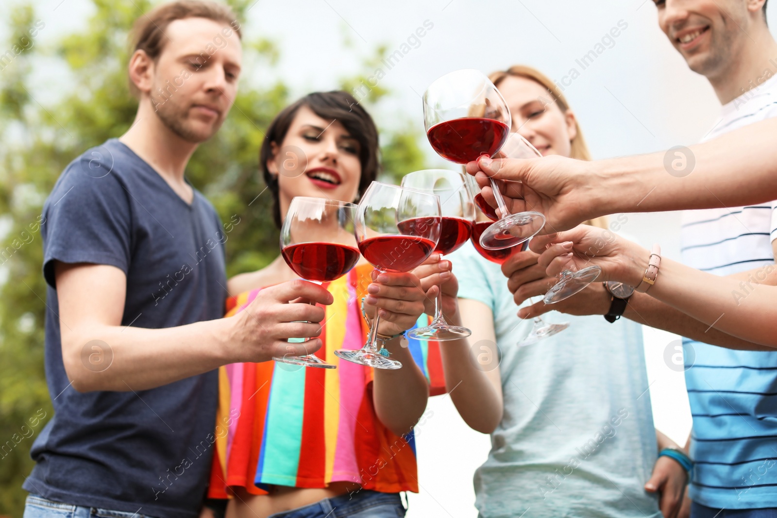 Photo of Young people with glasses of wine outdoors. Summer picnic