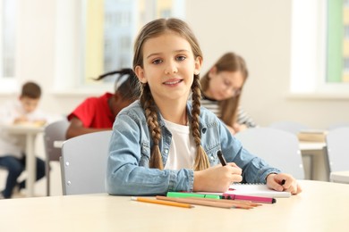 Photo of Portrait of smiling little girl studying in classroom at school