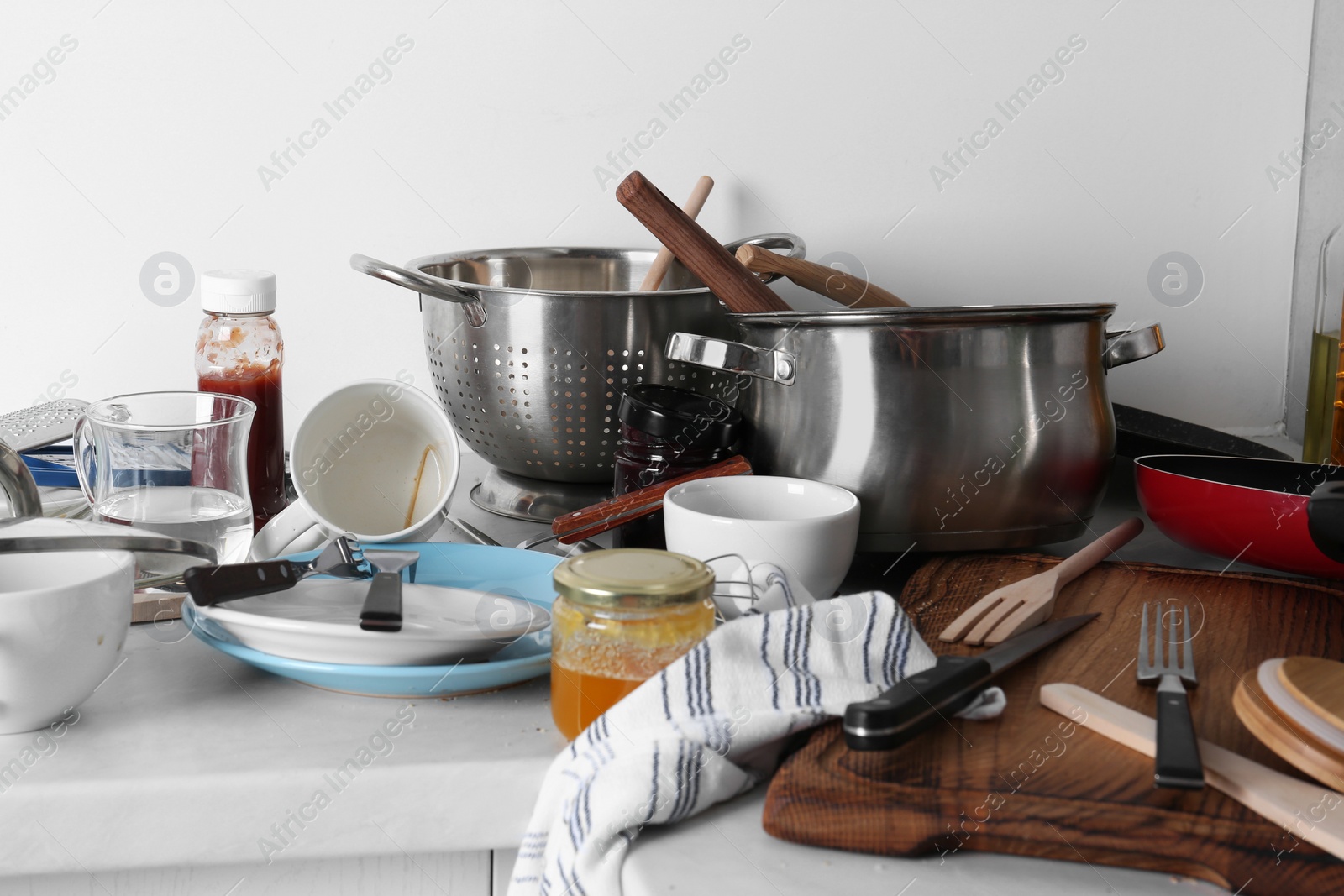 Photo of Many dirty utensils, cookware and dishware on countertop in messy kitchen