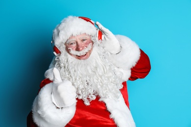 Photo of Authentic Santa Claus listening to music on color background