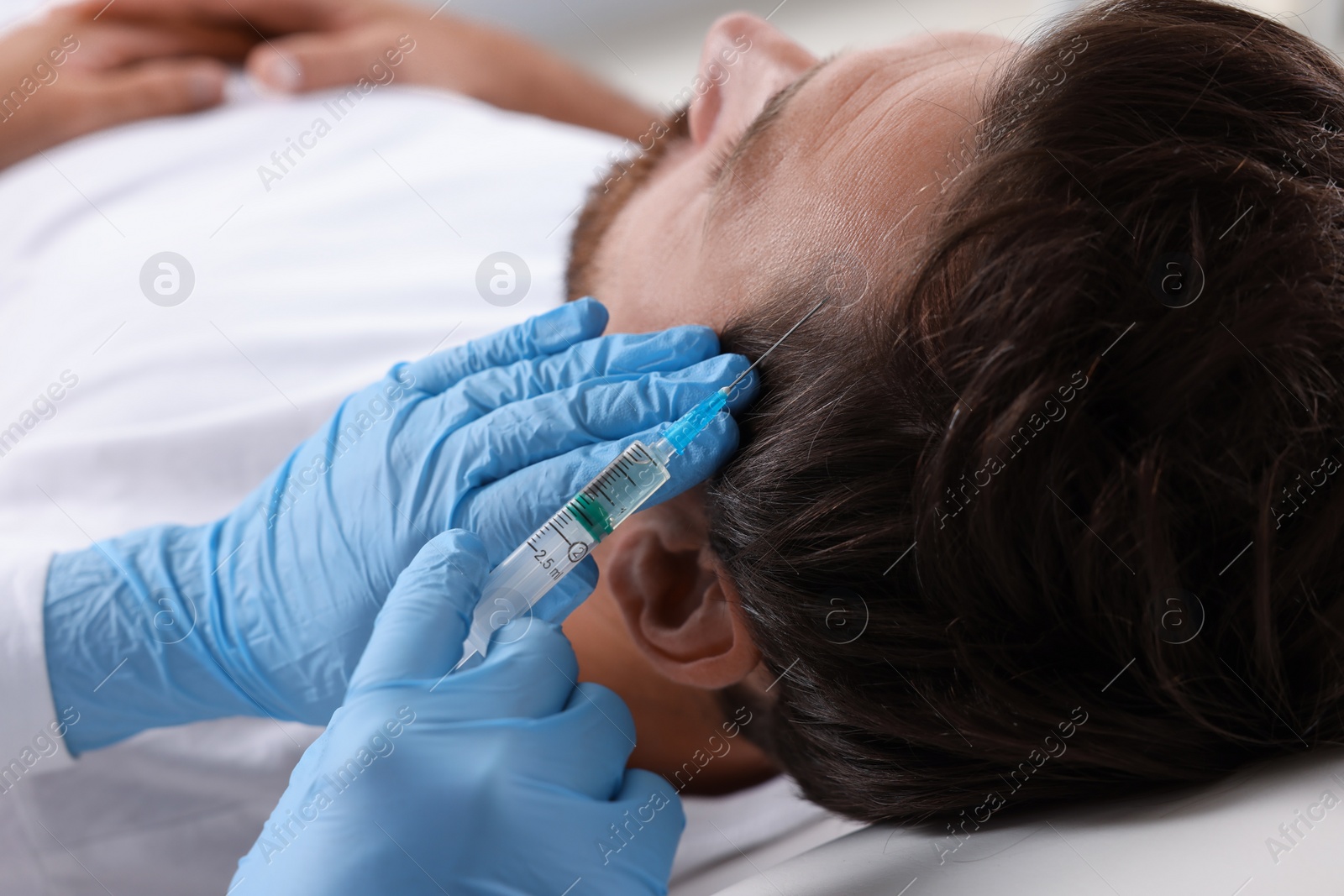 Photo of Trichologist giving injection to patient in clinic, closeup