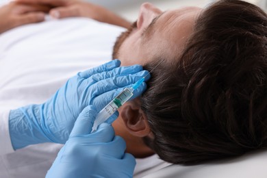 Photo of Trichologist giving injection to patient in clinic, closeup