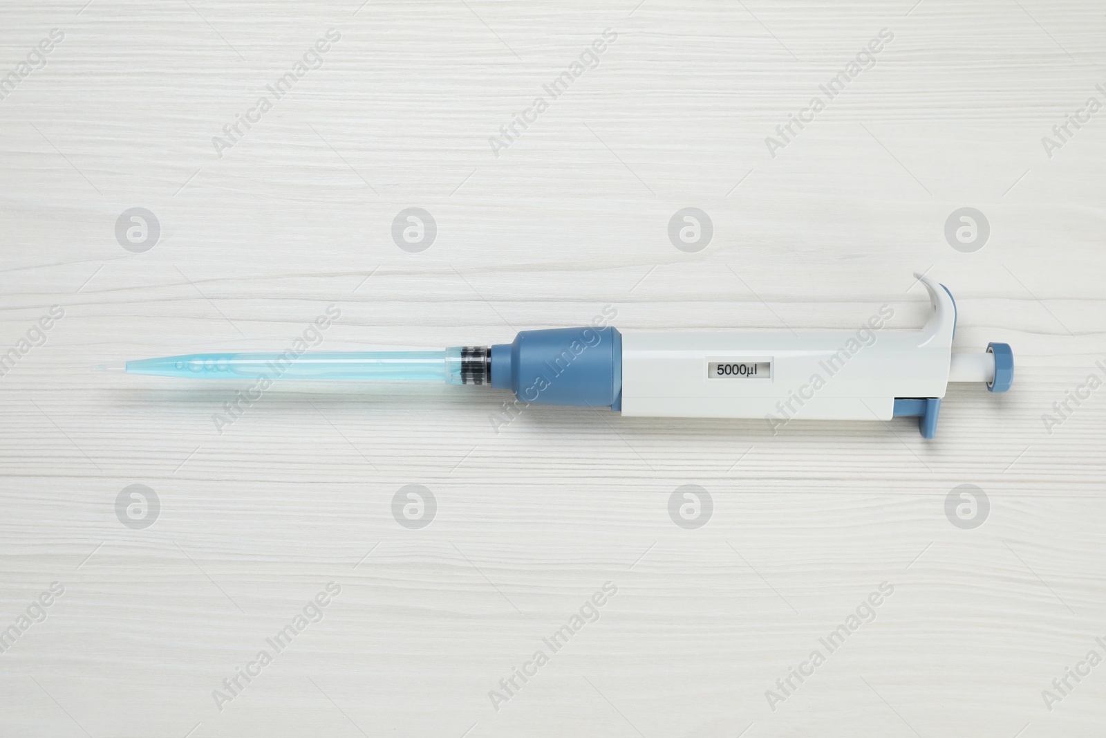 Photo of Laboratory analysis. Micropipette with liquid on white wooden table, top view