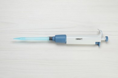 Laboratory analysis. Micropipette with liquid on white wooden table, top view