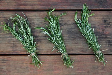 Photo of Bunches of fresh rosemary on wooden table, flat lay. Aromatic herb