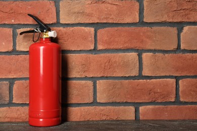 Photo of One red fire extinguisher near brick wall, space for text