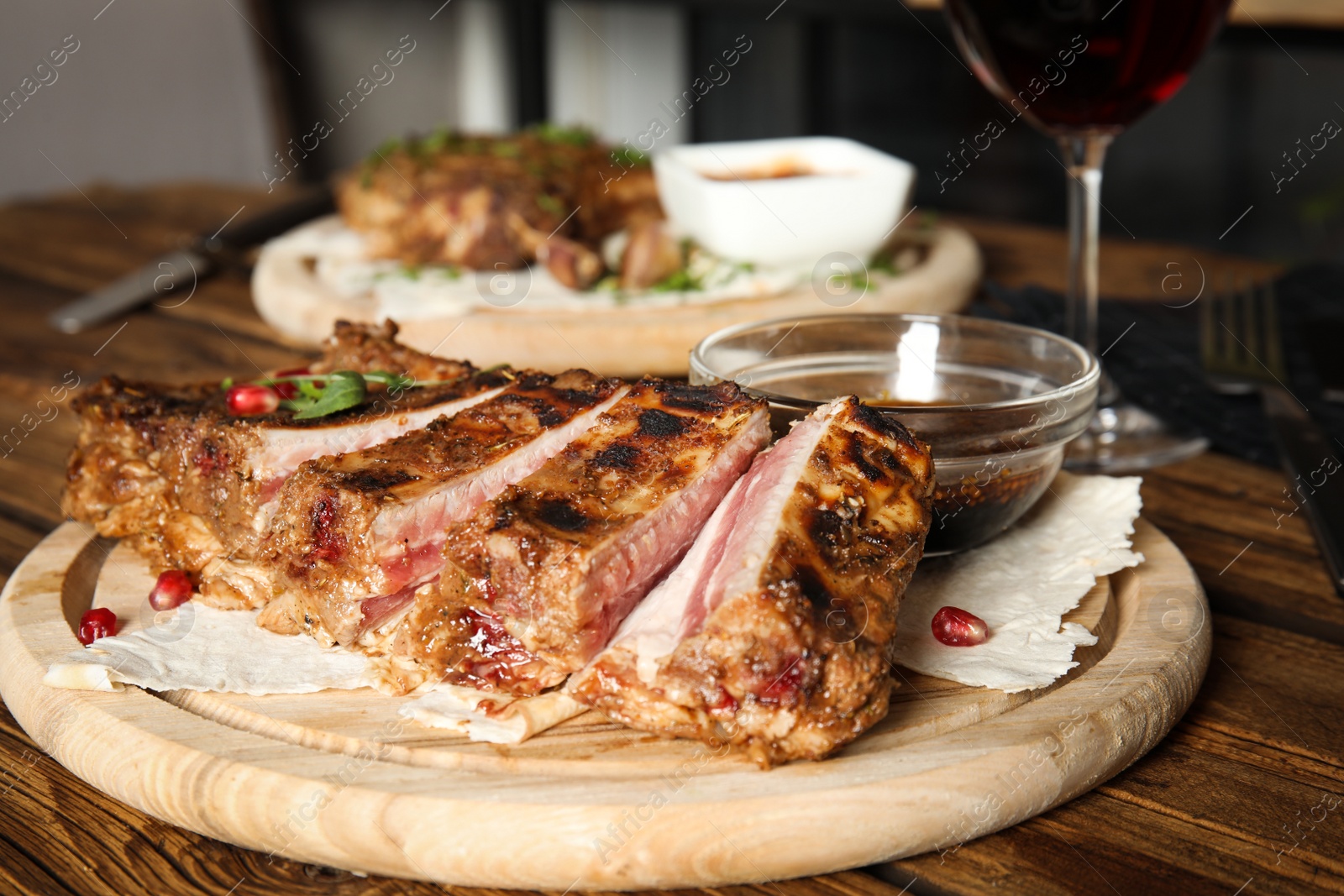 Photo of Delicious grilled ribs served on wooden table indoors