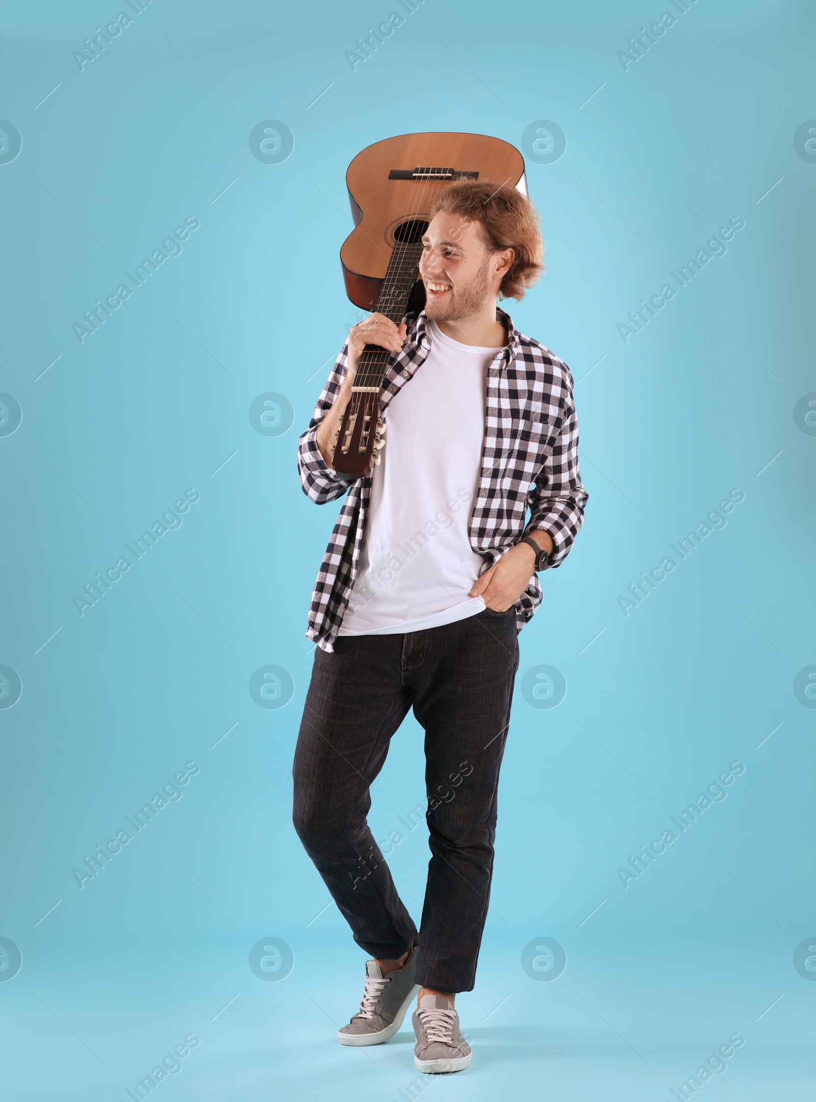 Photo of Young man with acoustic guitar on color background