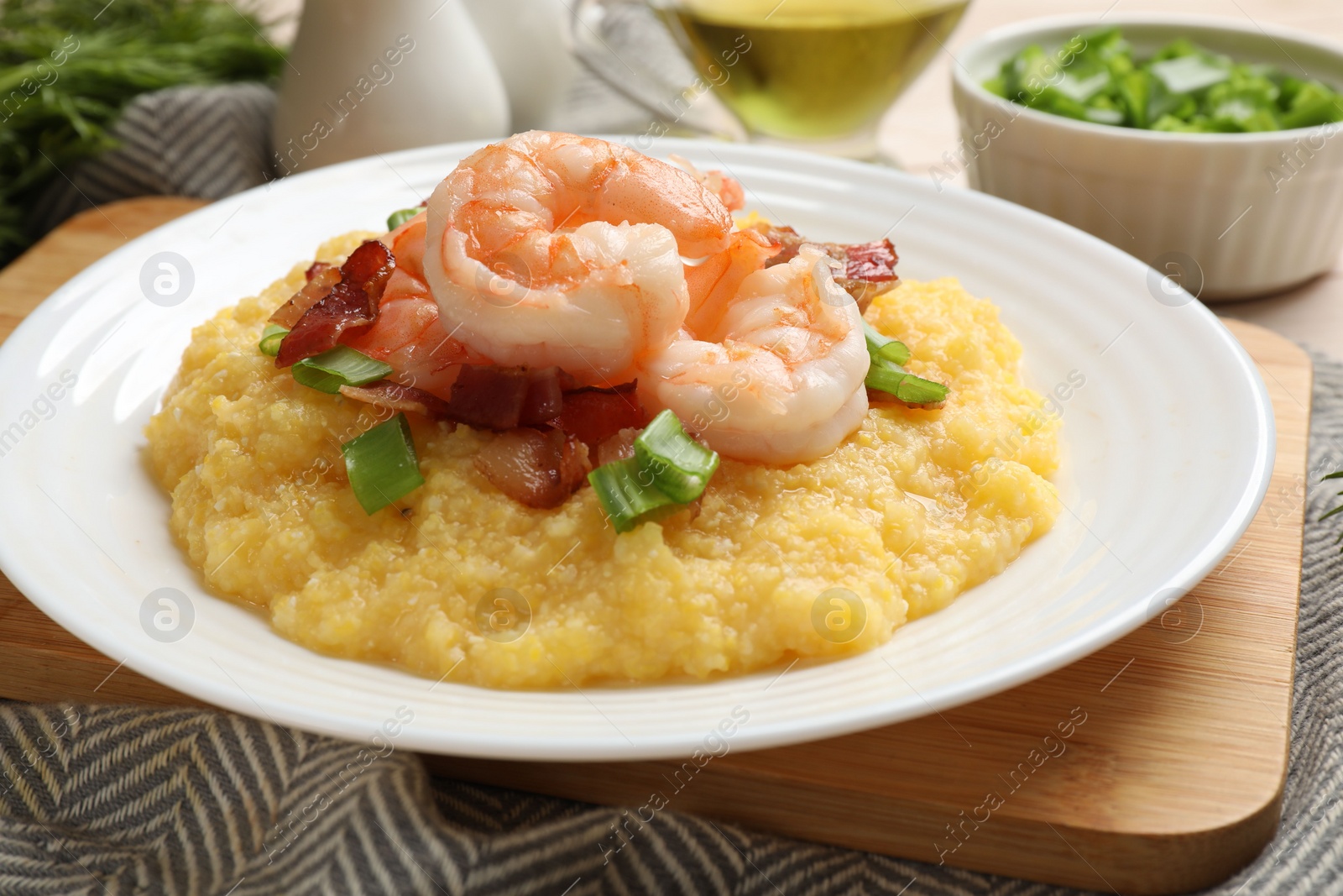 Photo of Plate with fresh tasty shrimps, bacon, grits and green onion on table, closeup