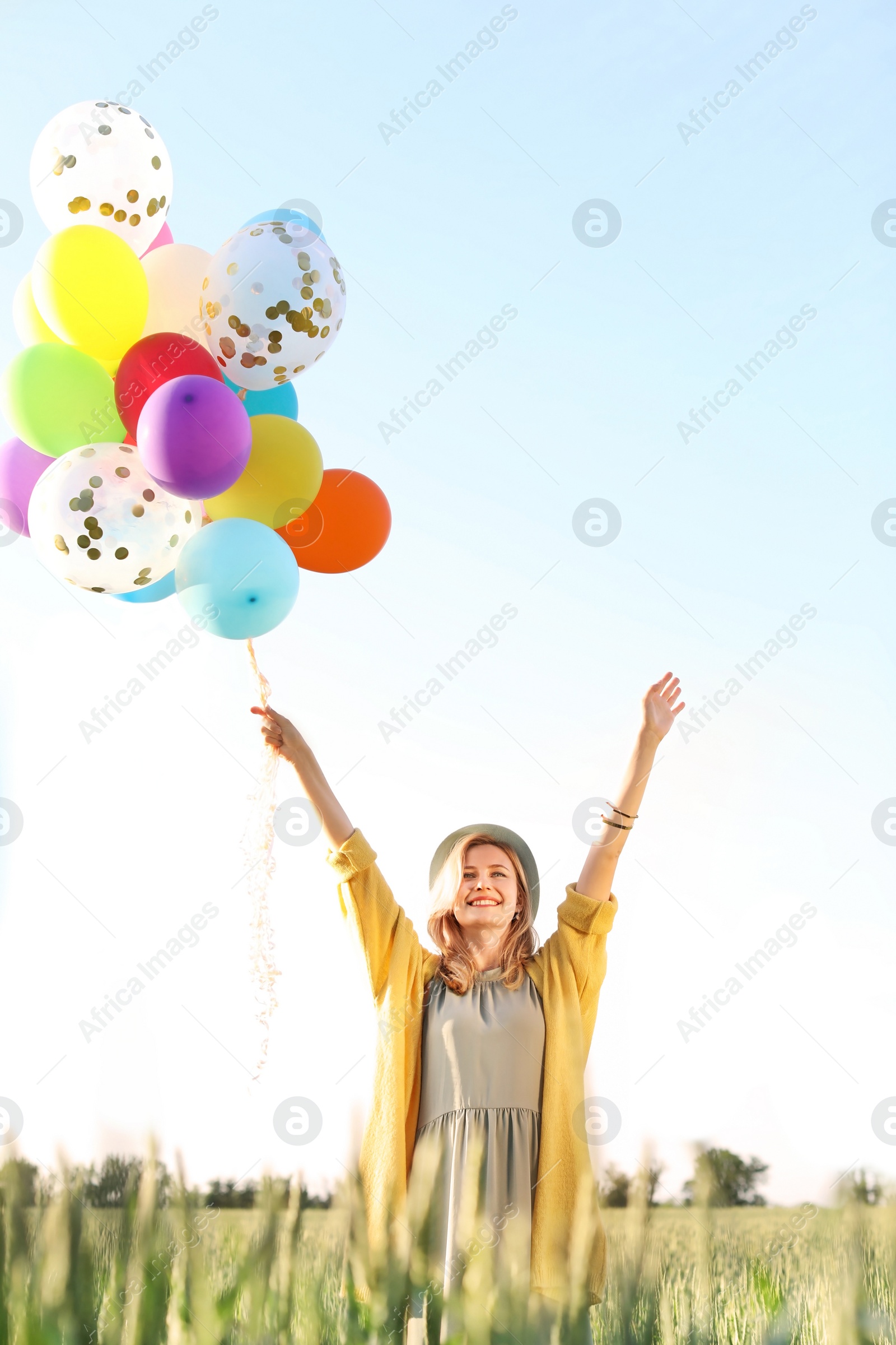 Photo of Young woman with colorful balloons outdoors on sunny day