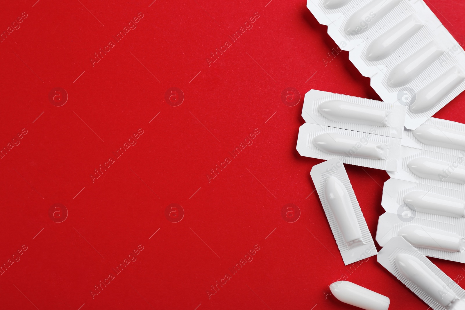 Photo of Suppositories and space for text on red background, flat lay. Hemorrhoid treatment