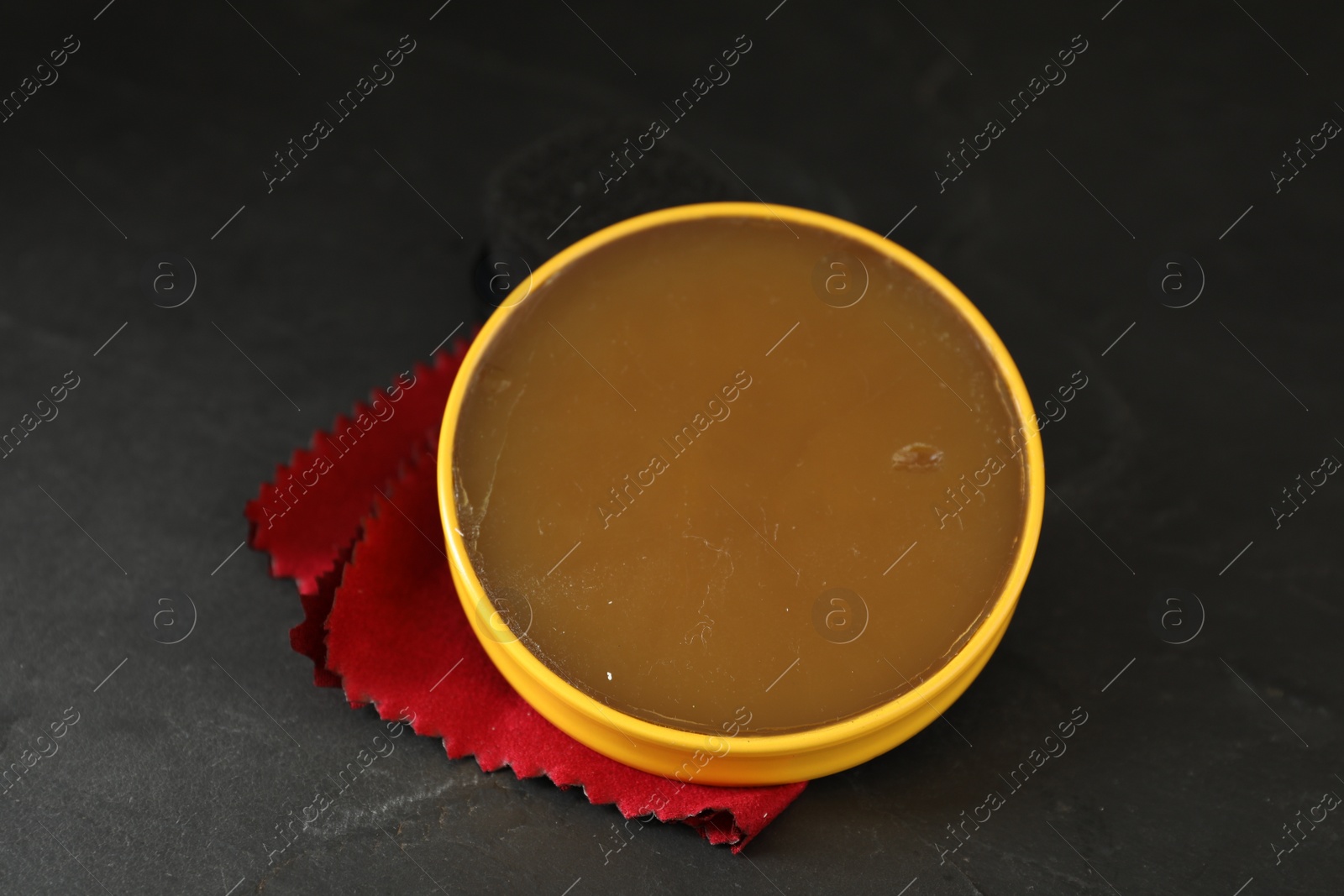 Photo of Can of shoe polish on black table, closeup. Footwear care item