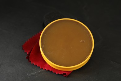 Photo of Can of shoe polish on black table, closeup. Footwear care item