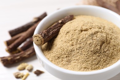Photo of Powder and dried stick of liquorice root in bowl, closeup