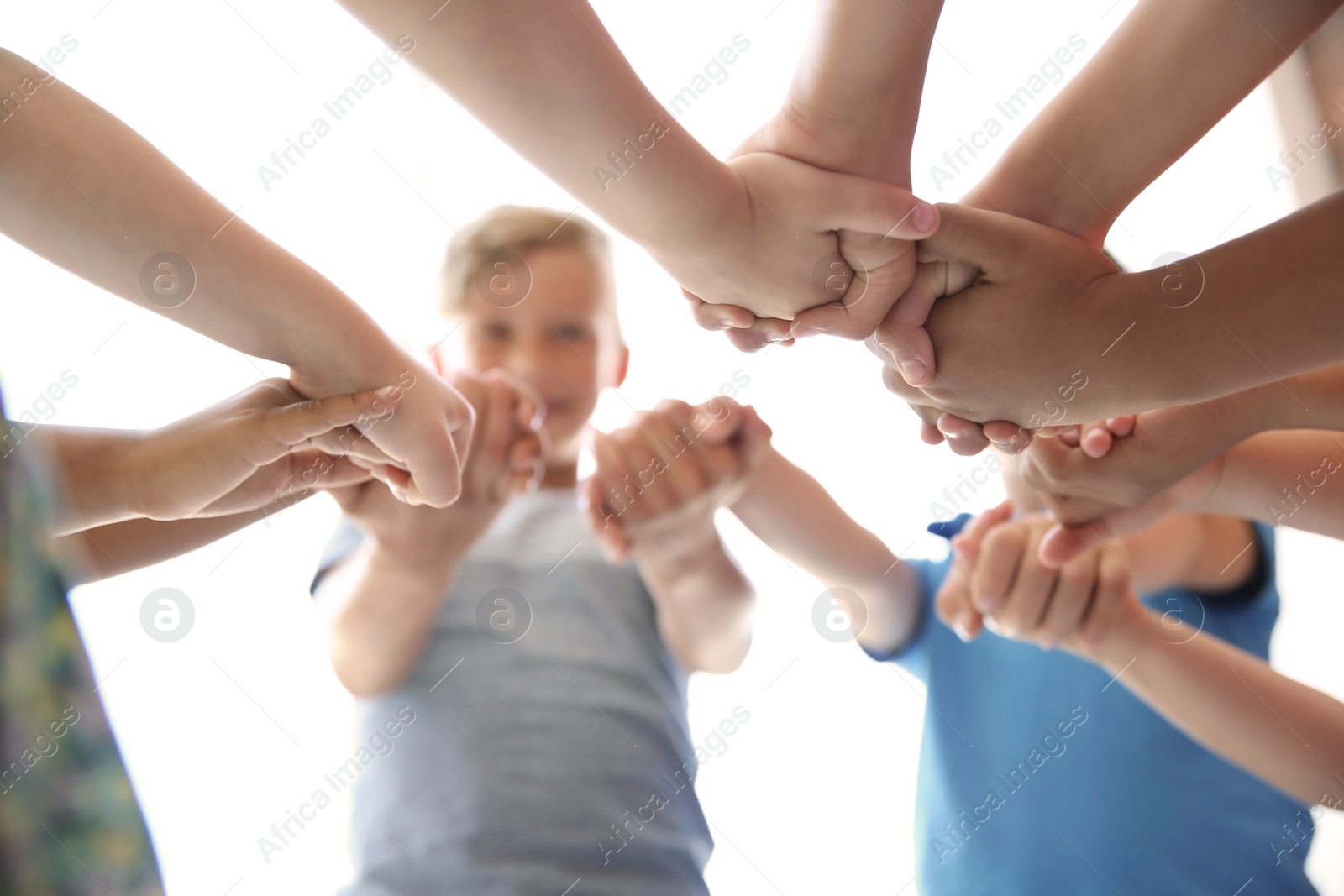 Photo of Little children holding their hands together on light background. Unity concept