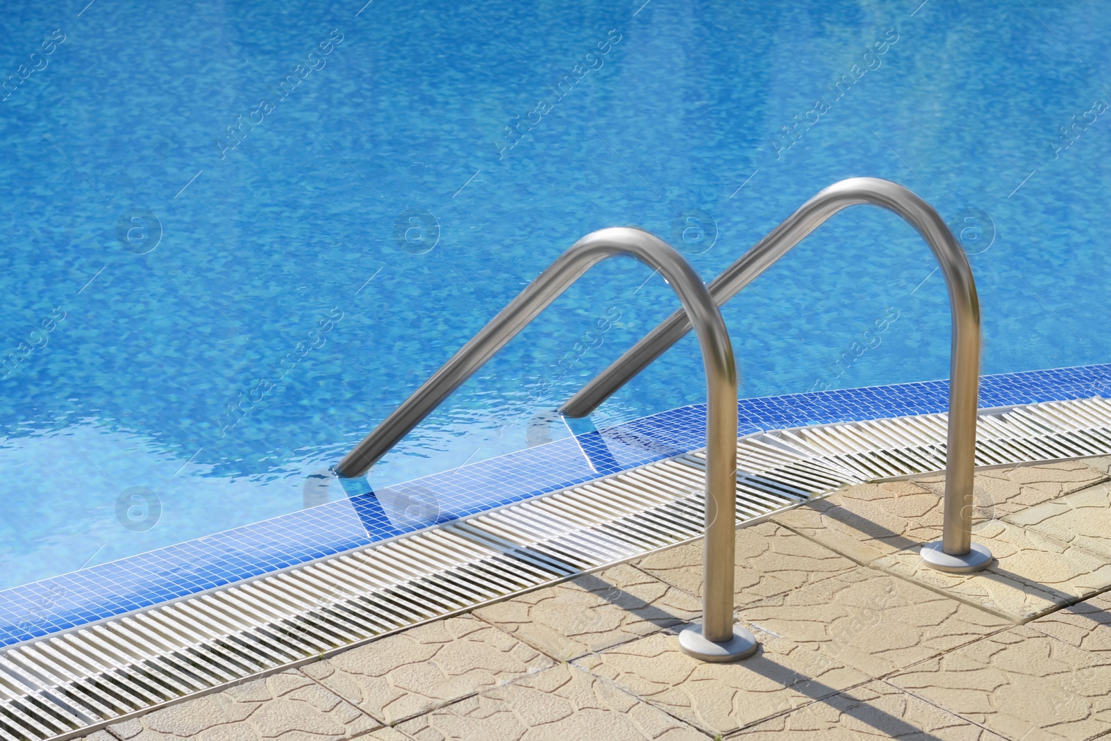 Photo of Outdoor swimming pool with ladder and handrails on sunny day