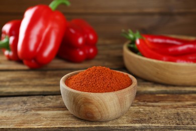 Bowl of paprika with peppers on wooden table