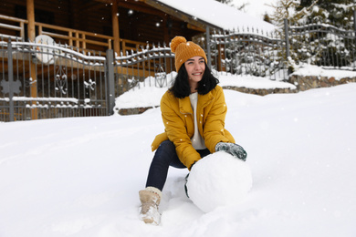 Photo of Happy woman making ball for snowman outdoors. Winter vacation