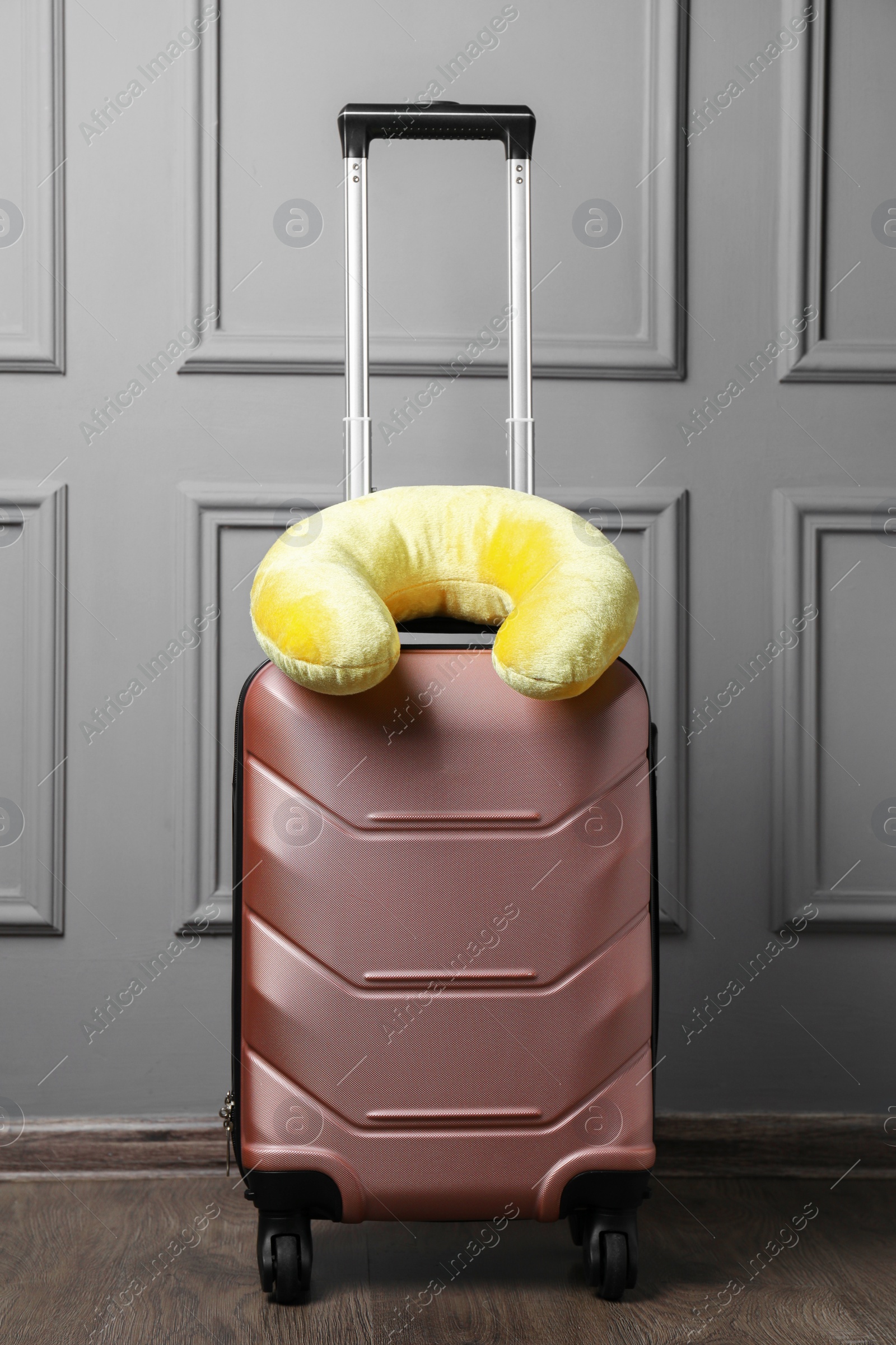 Photo of Yellow travel pillow on suitcase near light wall indoors