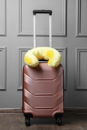 Photo of Yellow travel pillow on suitcase near light wall indoors