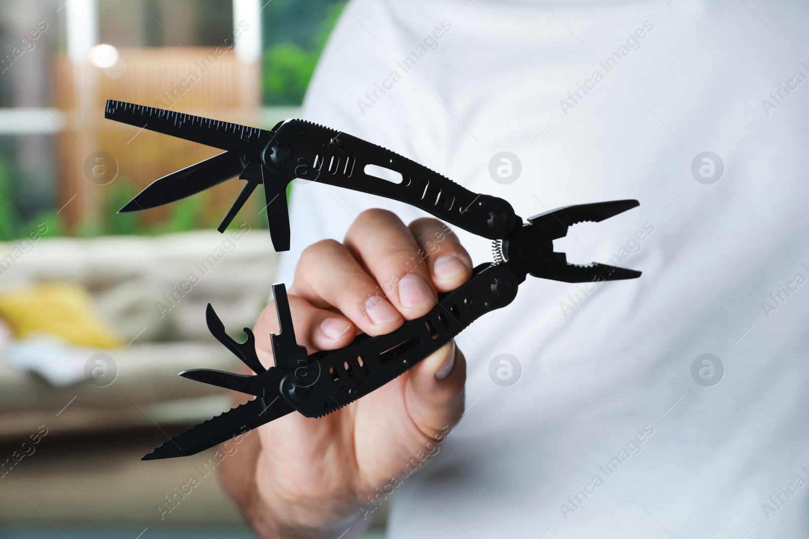 Photo of Man holding compact portable multitool indoors, closeup