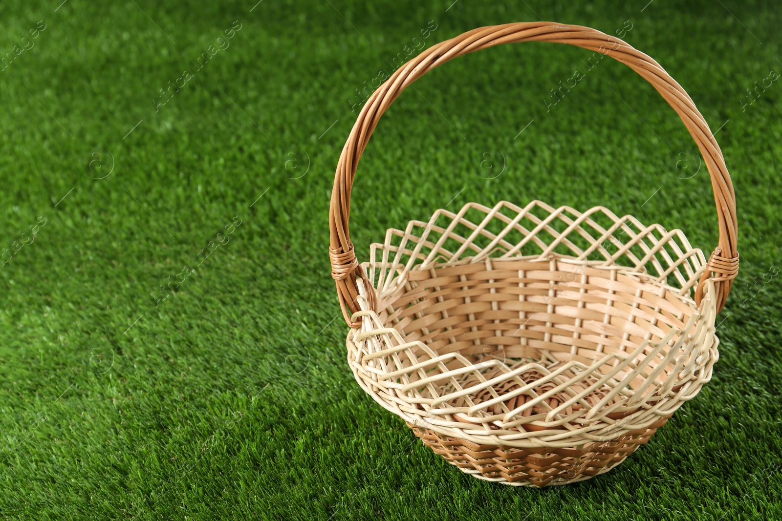 Photo of Empty wicker basket on green lawn, space for text. Easter item